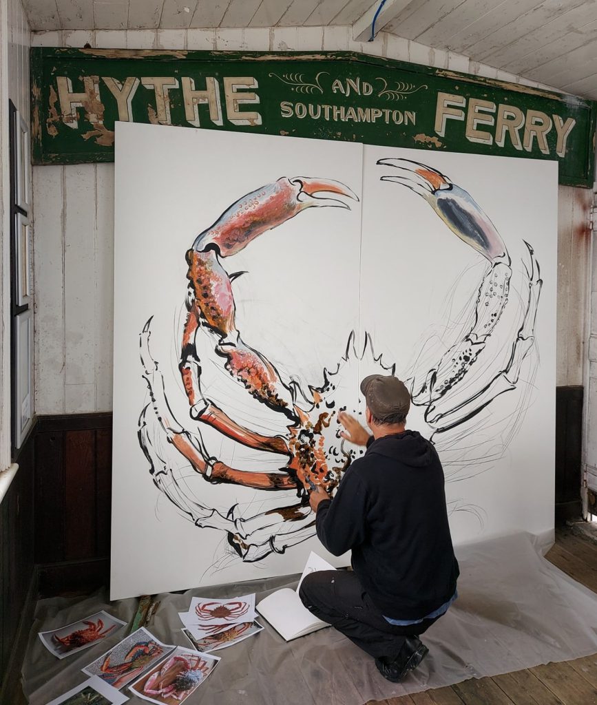 Artist creating a large mural of a spider crab in the waiting room of Hythe pier